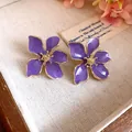 Macro detail view of elegant purple oil-dripped flower stud earrings with gold edges - Tops / Purple