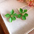 Detailed view of sweet green enamel flower stud earrings with elegant gold accents - Tops / Green