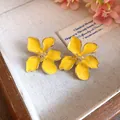 Close-up of elegant yellow enamel flower earrings with gold-tone edges and center - Tops / Yellow