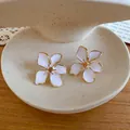 Close-up view of elegant white drip oil flower stud earrings featuring golden trim details - Flower / White