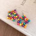 Détail de boucles d'oreilles en perles de bois colorées sur un fond de livre en lin. - Argent - Arc-en-ciel