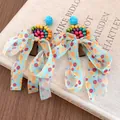 Vue détaillée de boucles d'oreilles bohèmes en perles de bois avec nœuds en mousseline - Coloré