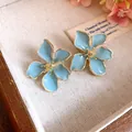 Elegant light blue flower stud earrings with gold trim for a fresh summer look - Tops / Blue