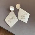 Close-up detail of matte silver rhombus earrings with an embossed floral branch design - Silver Earring Post Style / Silver