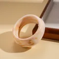 Close-up of wide irregular resin bangle with elegant cream and brown marble texture - Beige