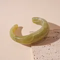 Close-up detail of an olive green irregular resin bangle with white marble texture - Green