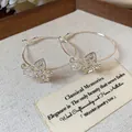 Close-up of elegant silver hoop earrings featuring hollow zircon butterfly charms - Hollow Flower / Silver