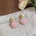 Close-up of elegant pink rose drop earrings with white leaf detail on beige pouch - Earrings / 925 Silver Needle / Gold-White-Pink