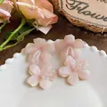 Macro view of pink chiffon flower earrings with clear glass bead centers on white plate. - Pink