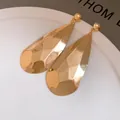 Vista detallada de pendientes de gota facetados dorados con acabado metálico brillante - Brillante / Dorado