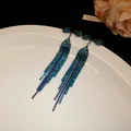 Close-up of blue rhinestone tassel earrings with bow design on a white plate - Gun Black-Green