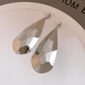 Primer plano de pendientes minimalistas de gota de agua plateada con acabado facetado - Brillante / Plateado