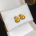 Close-up of golden pearl stud earrings with zircon detail presented in a white jewelry box - Gold - Champagne
