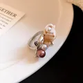 Vista dettagliata dell'anello bohémien con conchiglia e perle rosa e bianche su ceramica. - Stile Conchiglia di Perle Rosa Viola (9)