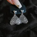 Detailaufnahme der hohlen herzförmigen Ohrringe mit metallischer Silbertextur - Hohlherz-Stil / Silber