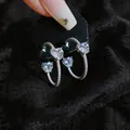 Nahaufnahme von herzförmigen Kristallohrringen mit mikrogepflasterten Creolen auf Spitze - Strass Herz Stil / Silber