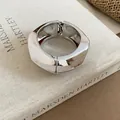 Professional detail shot of a chunky irregular silver wide bangle bracelet on a linen book. - Silver