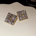 Dettaglio di orecchini quadrati con cristalli blu chiaro e montatura dorata - Oro