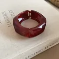 Primo piano di un bracciale rigido in resina rosso ambra con fascia larga e chiusura. - Borgogna