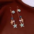 Detailed view of nautical bohemian drop earrings with teal starfish, golden shells and pearls - Earring Hooks / Gold, Blue