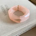 Dettaglio di un bracciale rigido largo e irregolare in resina pesca su un libro - Rosa
