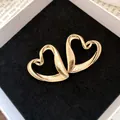 Macro detail of interlocking gold double-heart earrings on black velvet - Gold