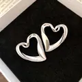 Detailed close-up of vintage silver heart-shaped earrings with a unique textured twisted design - Silver