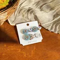 Detailed macro view of elegant resin flower and rhinestone bow hair clips on card. - Blue (1 Pair) / Silver
