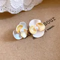 Close-up detail of elegant bi-color enamel flower earrings with central pearl accents - Silver Needle / Yellow