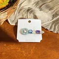 Close-up of elegant hair clip featuring colorful resin, crystals, and a Lucky charm tag - Purple-Blue (Single) / Silver