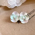 Macro view of elegant mint green flower stud earrings with central pearl detail accent. - Silver Needle / Green