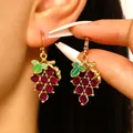 Primer plano de elegantes pendientes de uva dorados con gemas púrpuras y hojas de esmalte - Pendientes en Forma de Uva (WG-0627)