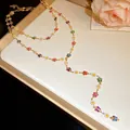 Elegant detail of a Y-shaped necklace with colorful butterfly and daisy charms - Gold-Multicolor