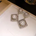 Κοντινό πλάνο από vintage ασημένια κρεμαστά σκουλαρίκια με πέρλες και λαμπερά ζιργκόν - Ασημί
