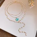 Detailed view of layered gold necklace with elegant blue flower pendant and pearls - Gold-Blue