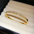 Detail of elegant gold stainless steel bangle featuring channel-set cubic zirconia stones. - 排钻方钻款式 / Gold