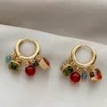 Close-up detail of 18k gold plated huggie hoop earrings with colorful zircon charms - Blue White Red Ear Buckle