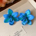Makroansicht von eleganten blauen Orchideen-Ohrringen aus Harz auf einem Leinentablett - Stil mit Silber-Ohrstecker / Blau
