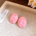 Close-up detail view of pink wrinkled oval stud earrings with elegant drop oil finish - Pink
