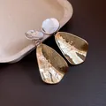 Vista dettagliata di orecchini a goccia martellati bicolore con finitura argento e oro. - Argento + Oro