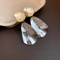 Dettaglio di orecchini bicolore con texture martellata su fondo in pelle - Oro + Argento