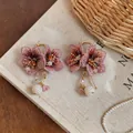 Detailed view of handmade knitted pink flower earrings with delicate pearl tassels. - Pink
