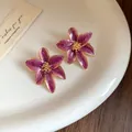 Détail de boucles d'oreilles fleurs en émail violet vintage avec bords dorés élégants - Violet