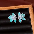 Primo piano di orecchini a lobo a fiore in smalto turchese con perle e zirconi. - Argento, Blu