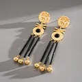 Close-up of vintage gold portrait earrings with black tassels and Greek fret details - Portrait Tassel Drop (HE34074) / Gold-Black