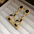 Close-up of vintage gold-tone triangle drop earrings with black and clear crystals. - Gold/Black