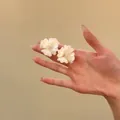 Primo piano di eleganti orecchini a fiore bianco con petali cristallini scintillanti su una mano - Gioielli con perno in argento / Bianco