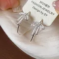 Detailed view of exquisite enamel bow-knot hoop earrings featuring S925 silver needles - White