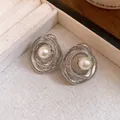 Close-up detail of vintage silver stud earrings featuring swirled circular design and pearl - Silver