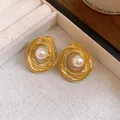Macro detail view of vintage gold-tone textured swirl stud earrings with central white pearls - Gold
